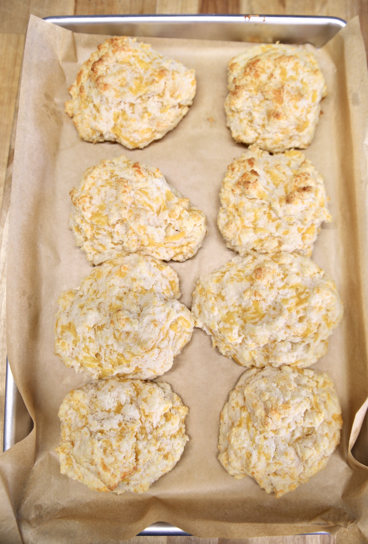 Baked cheddar biscuits on a sheet pan.