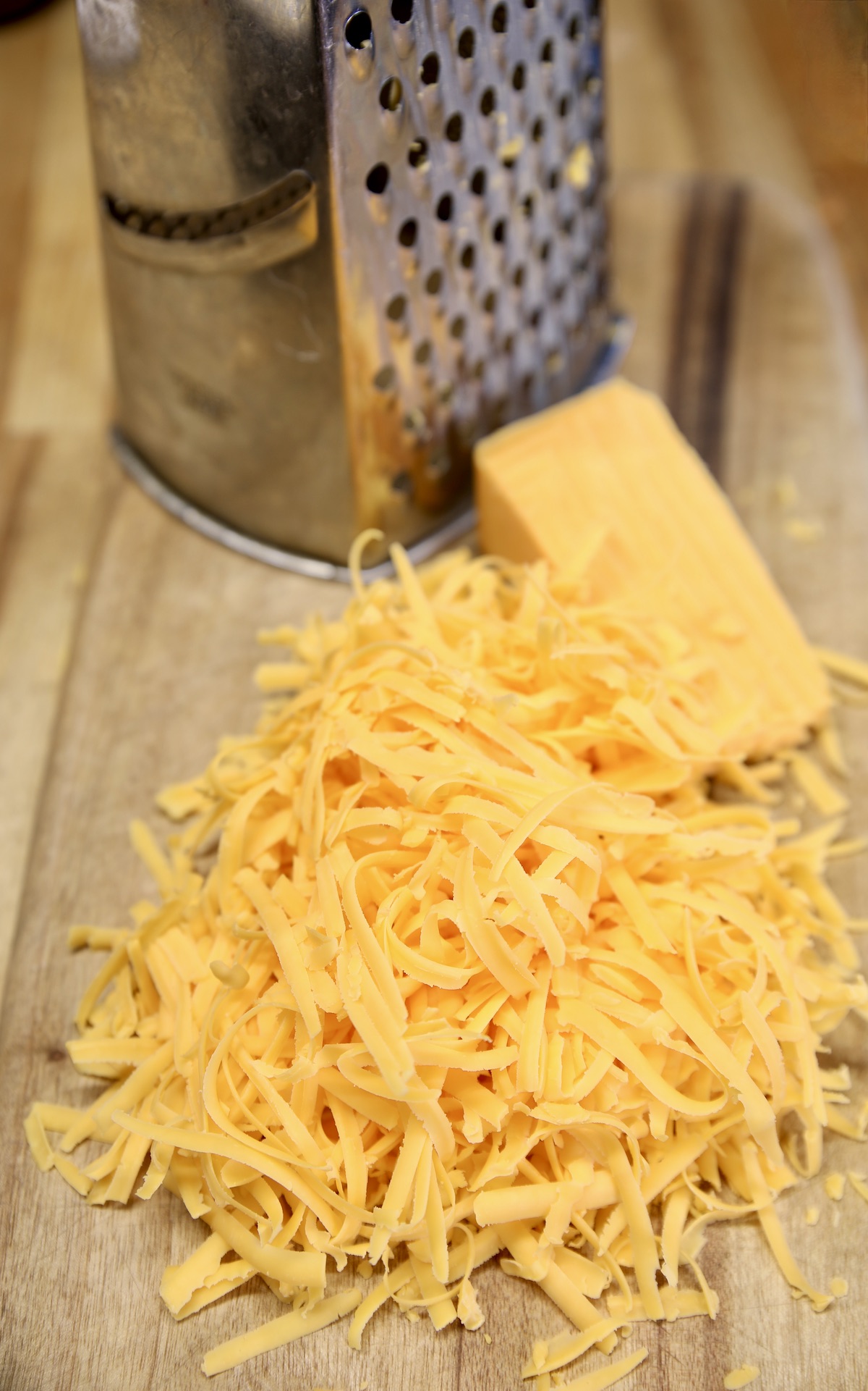 Box grater with chunk of cheddar, shredded.