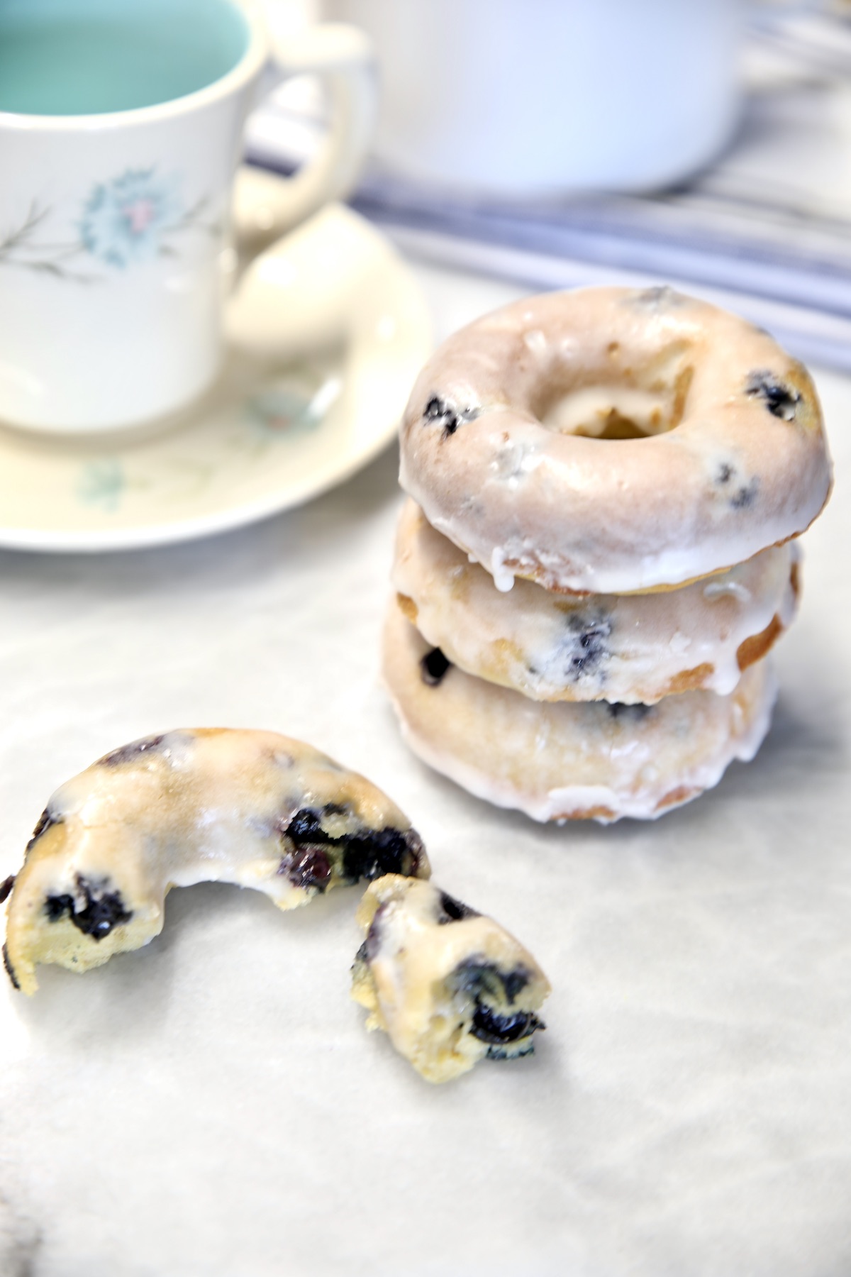 Blueberry donuts stacked with one partially eaten.