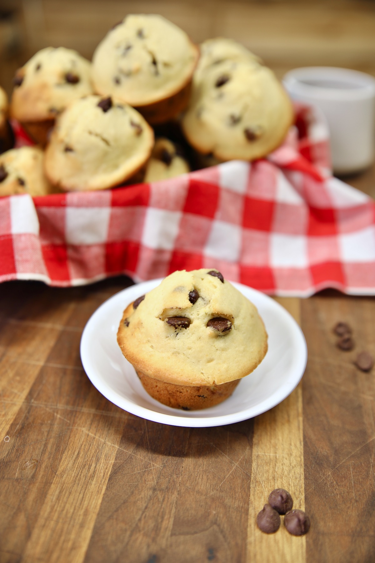 Chocolate chip muffins in a basket and one on a small plate.