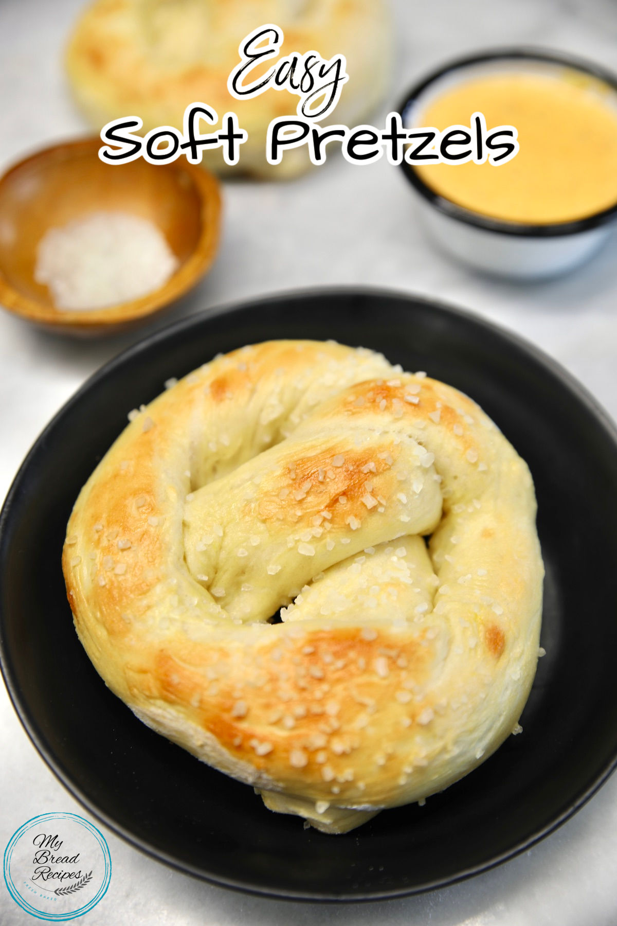 Soft pretzel on a plate, bowl of cheese, text overlay.