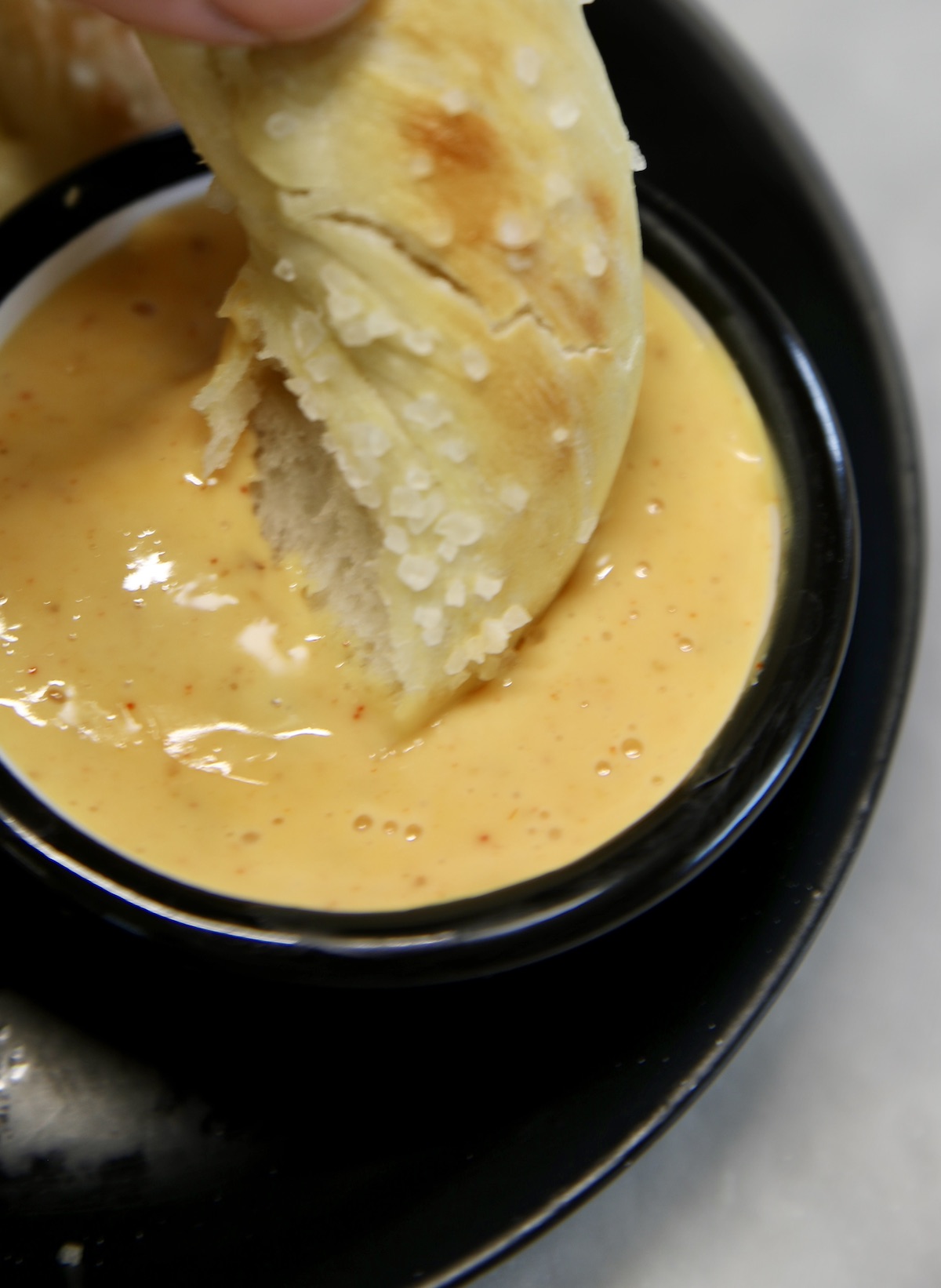 Dipping soft pretzel into cheese sauce.
