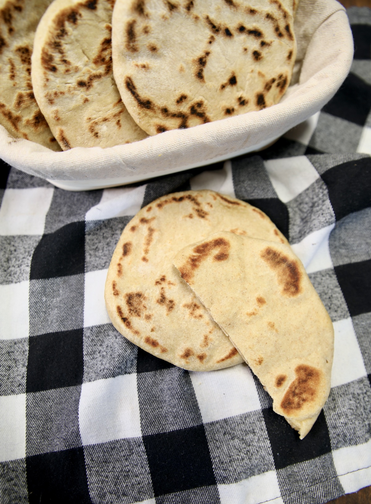 Basket of pita bread, with  one on a napkin and one cut in half.