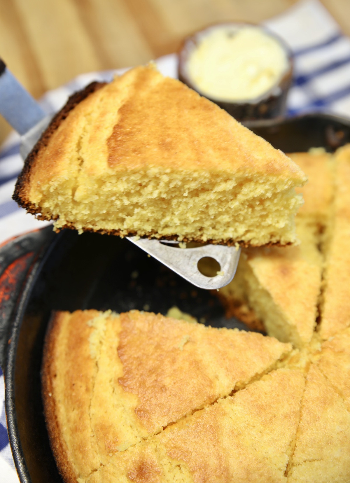 Wedge of cornbread serving from skillet.