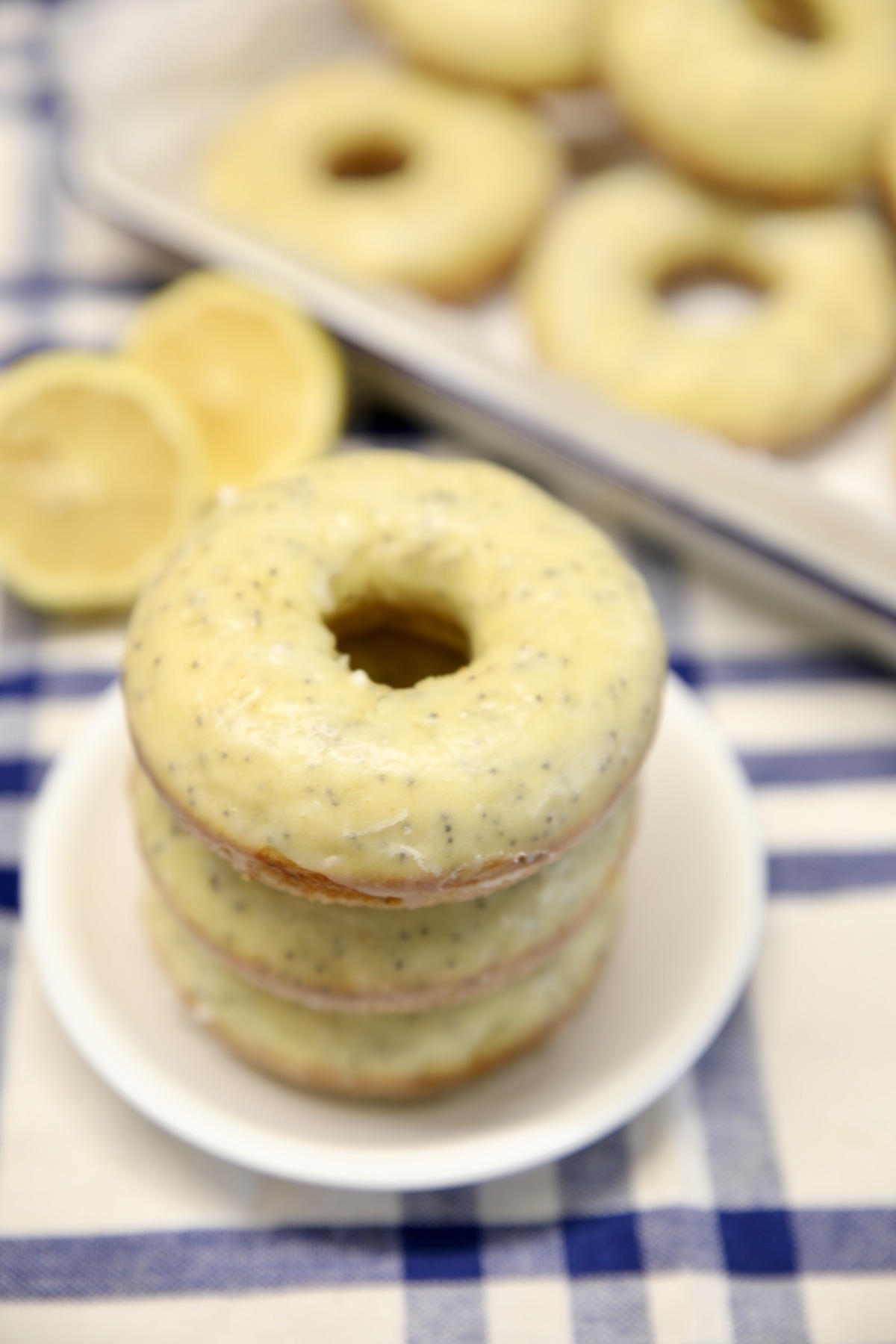 Stack of lemon glazed poppy seed donuts.