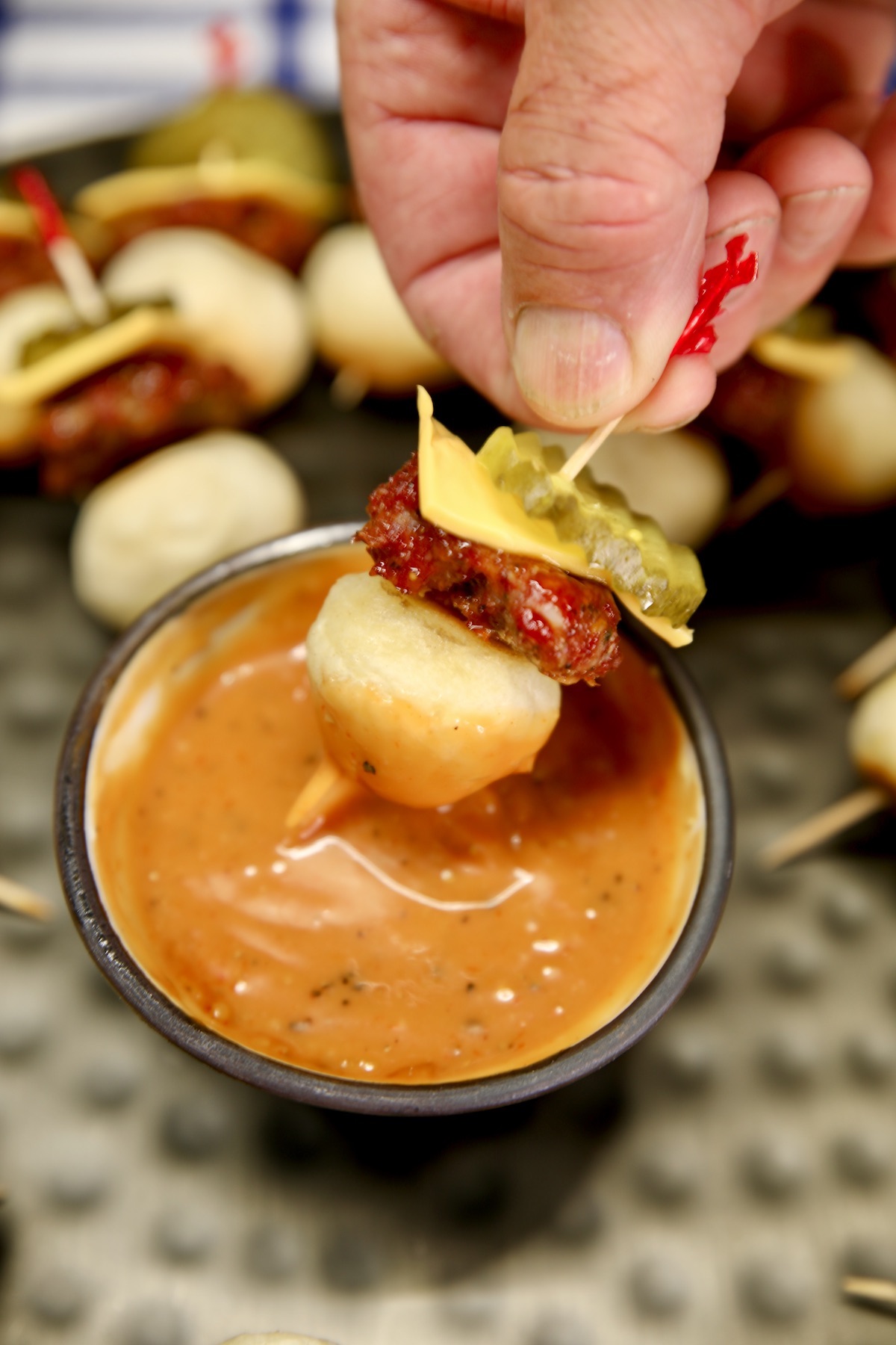 Garlic Bread Bite Burger appetizer dipping in sauce.