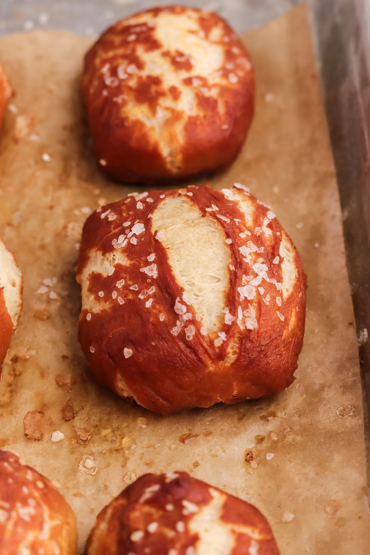 baked pretzel bites on a lined baking sheet, Three baked pretzel bites on a lined baking sheet.