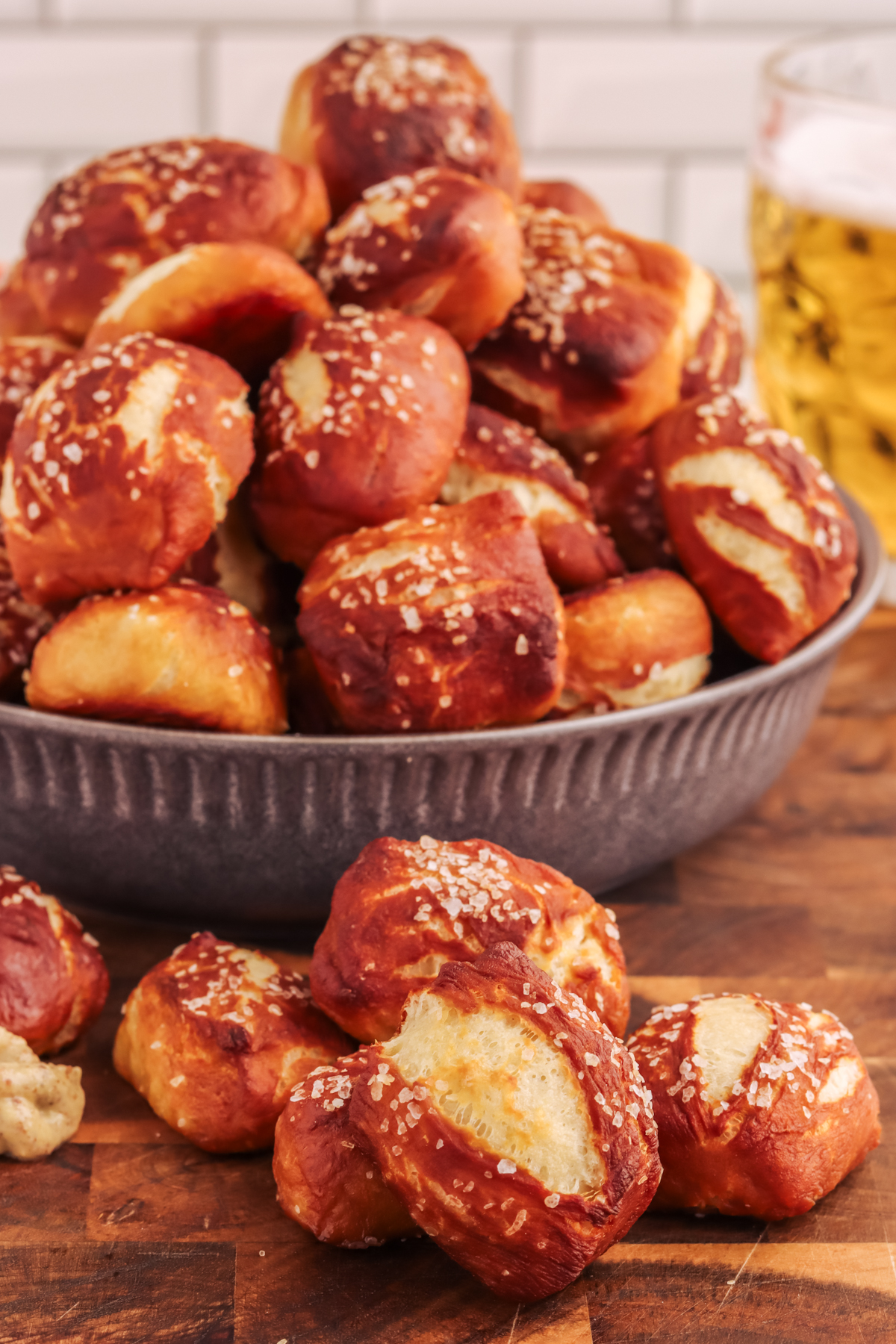 Bowl of pretzel bites on a wood platter. Baked salted pretzel bites in a bowl on a wood platter.