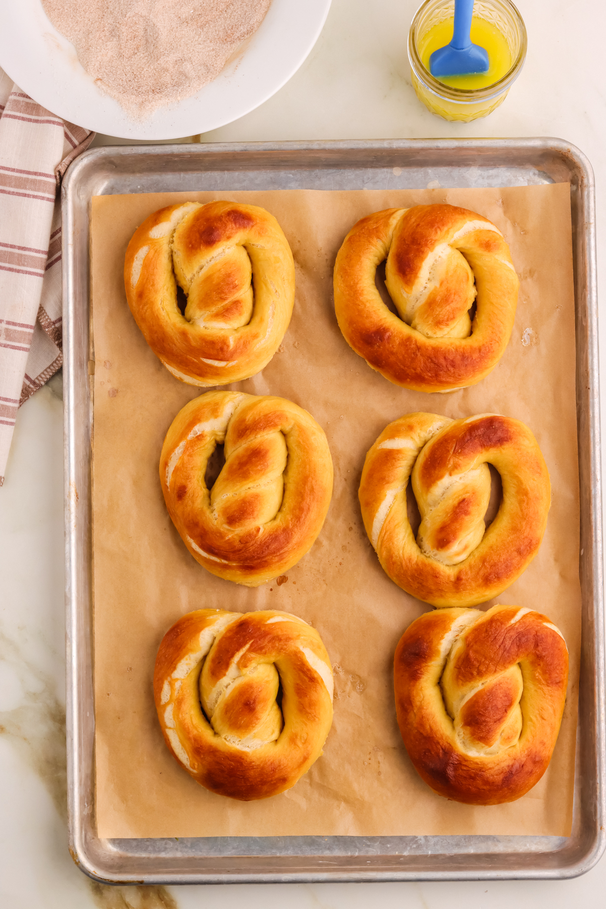 Fresh baked pretzels on a parchment lined baking sheet.