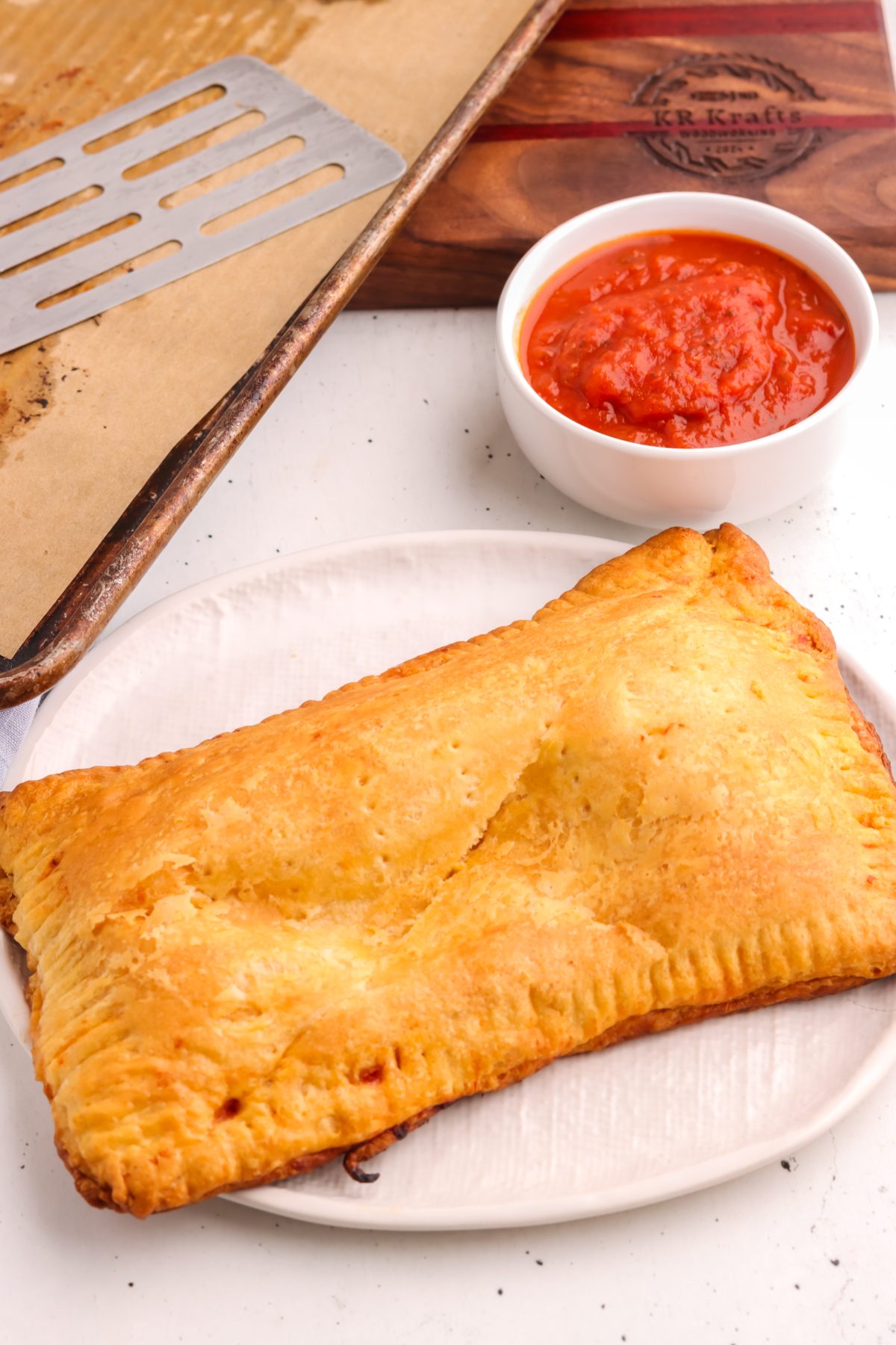 Baked pizza pockets on a white plate with marinara sauce. Baked pizza pockets on a white plate with marinara sauce.